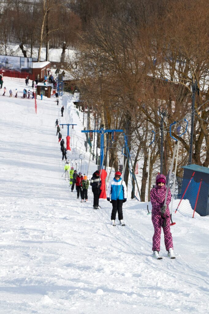People skiing up a snowy slope with ski lifts in the background
