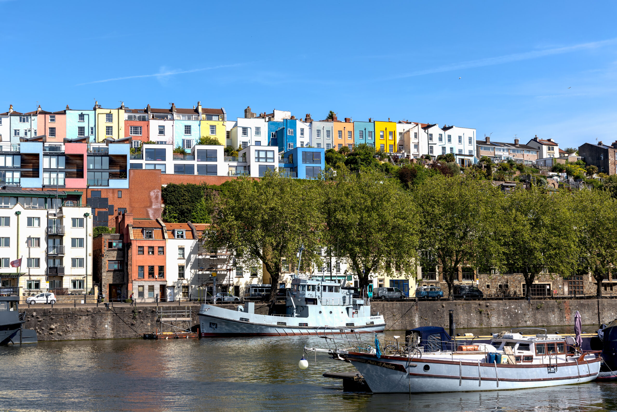 Boats moored on the River Avon in Bristol in front of colourful waterside apartments